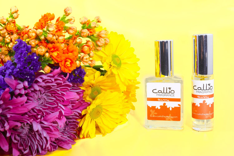 Sunny 1 oz and travel-size perfume on a yellow background with flowers to the left.