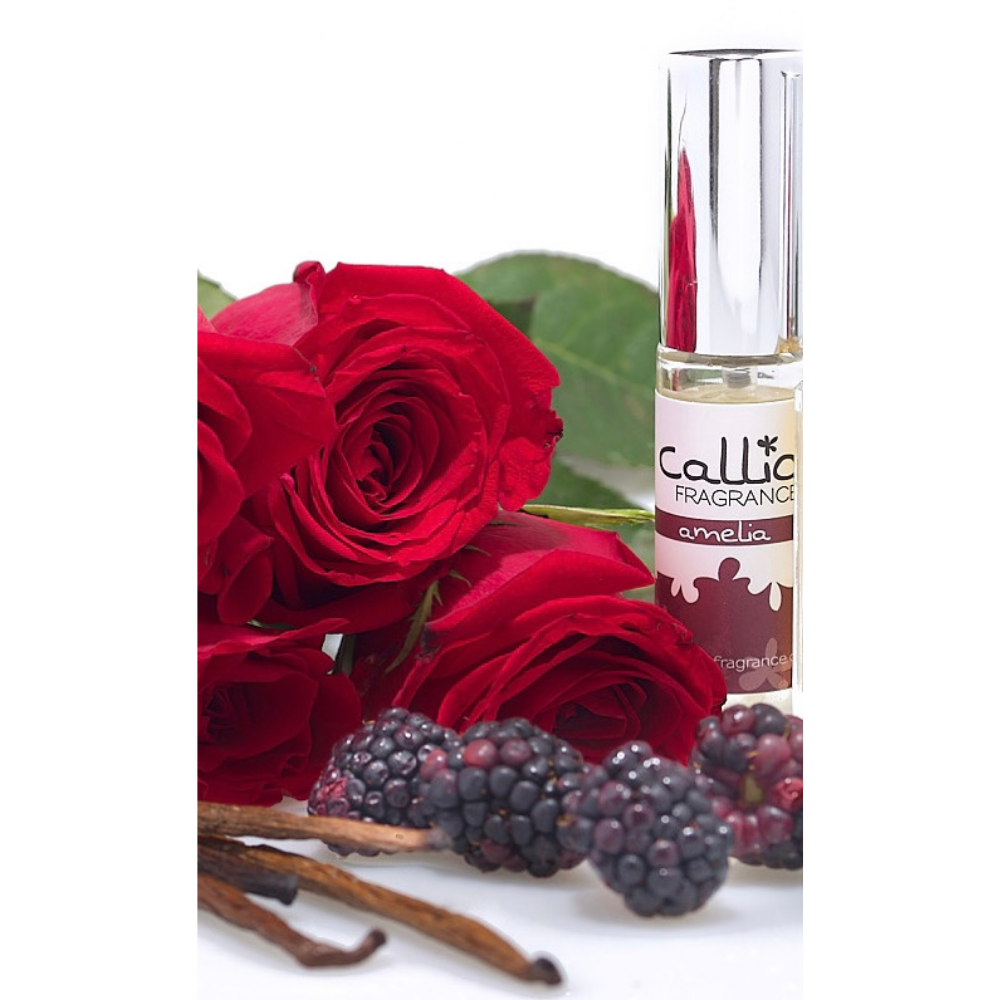 Image of a bottle of Amelia Travel-Size Perfume Spray by Callio Fragrance on a white background, surrounded by fresh blackberries., red roses, and vanilla beans.