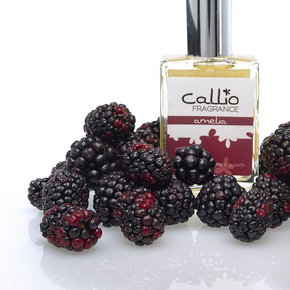 Image of a one-ounce bottle of Amelia Perfume by Callio Fragrance on a white background, surrounded by fresh blackberries.