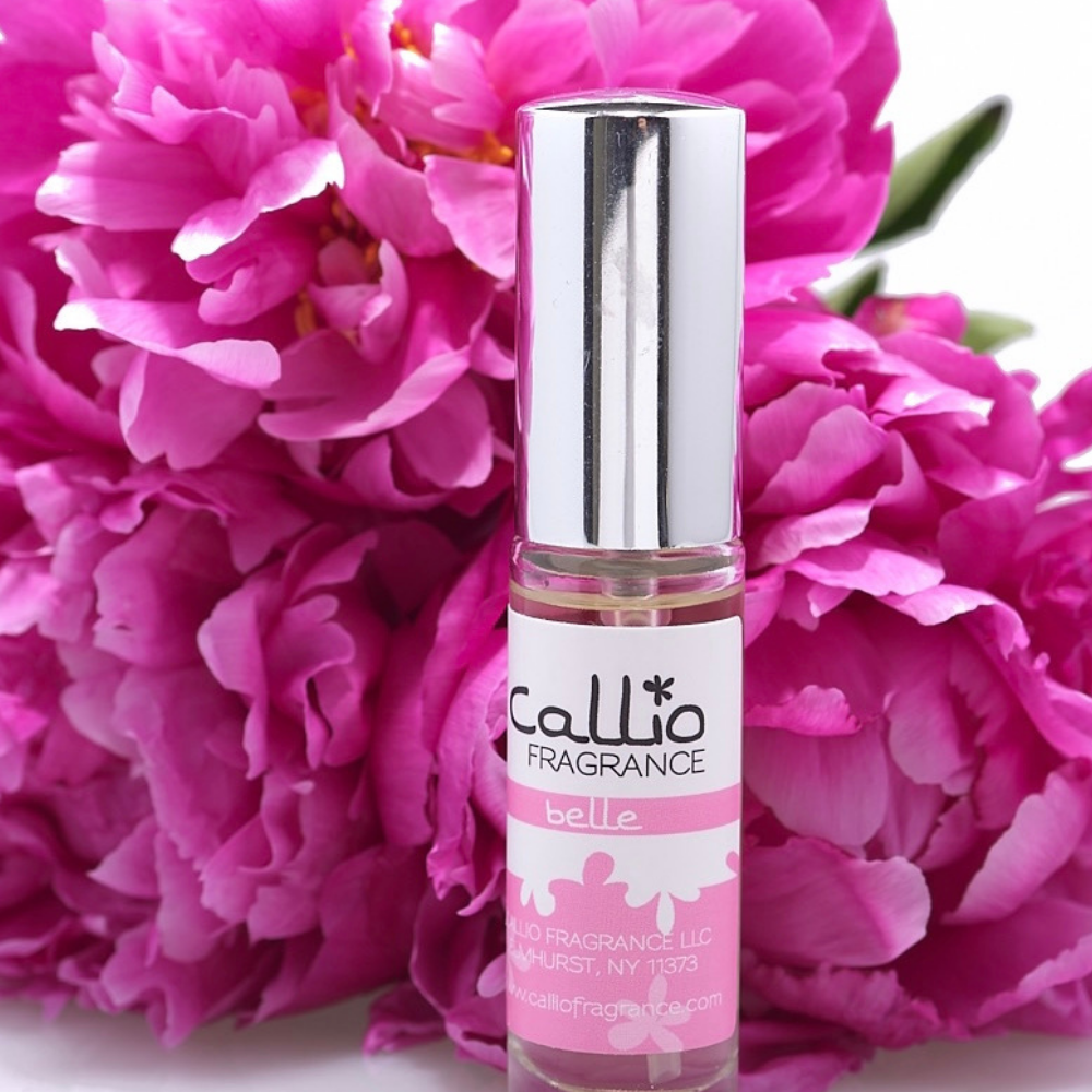 Image of a bottle of Belle Travel-Size Perfume on a white background surrounded by fresh-cut peonies.