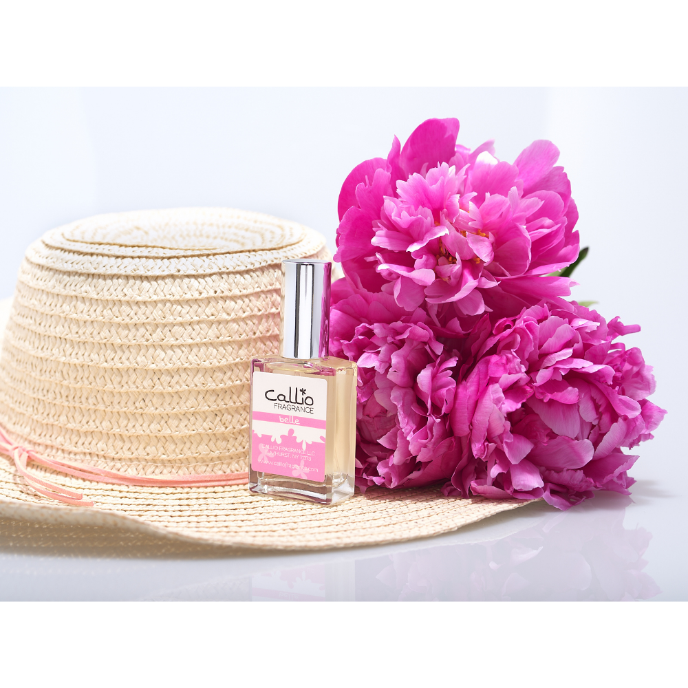 Image of a bottle of 1 oz. Belle Perfume by Callio Fragrance on a white background with a straw hat and peonies.