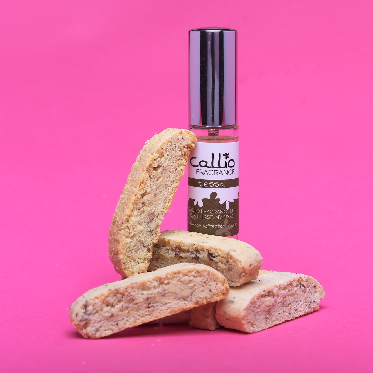 Tessa Travel Spray Perfume with six biscottis on a bright pink background.