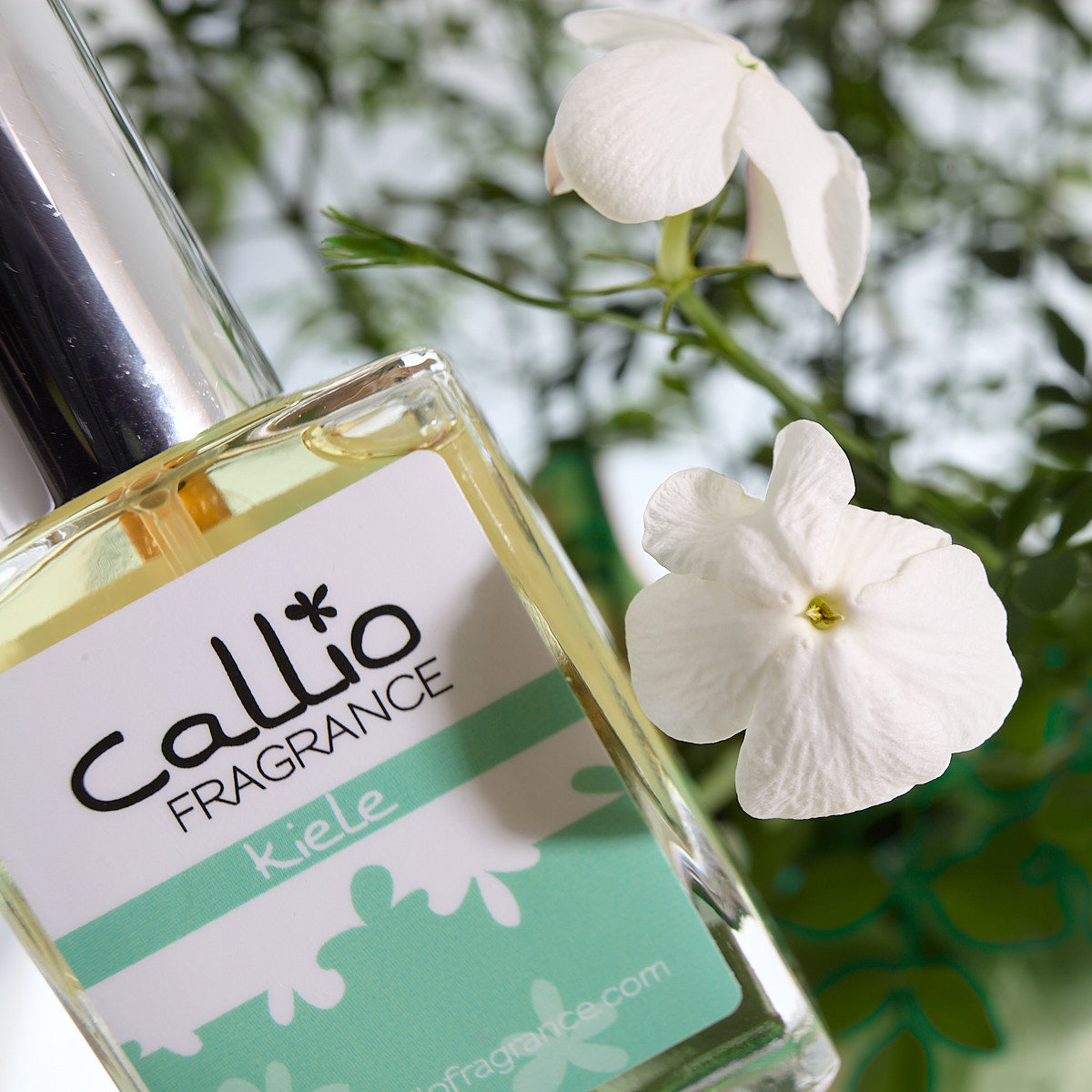 Image of a one-ounce bottle of Kiele Perfume by Callio Fragrance with jasmine flowers next to it.
